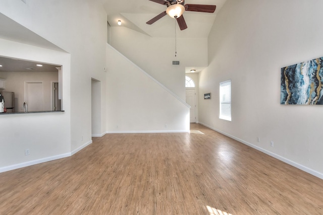 unfurnished living room featuring ceiling fan, light hardwood / wood-style floors, and high vaulted ceiling