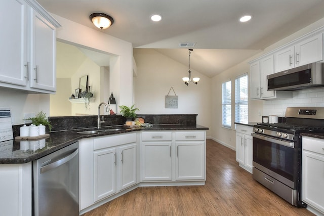 kitchen with lofted ceiling, white cabinetry, and appliances with stainless steel finishes