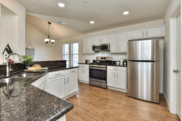 kitchen with sink, stainless steel appliances, white cabinets, and vaulted ceiling