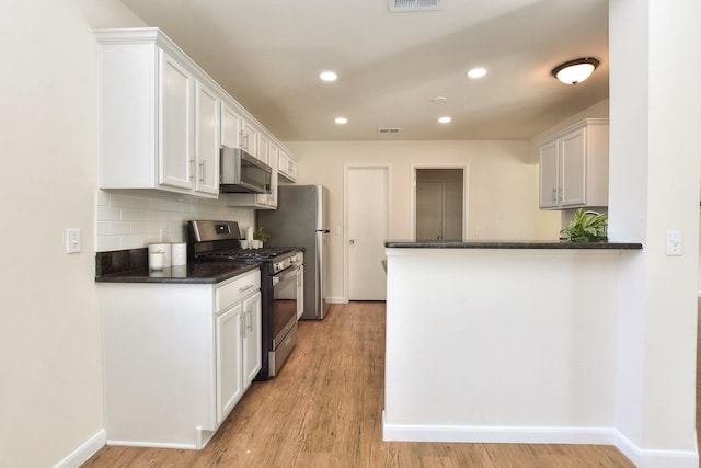 kitchen with kitchen peninsula, stainless steel appliances, light hardwood / wood-style floors, decorative backsplash, and white cabinets