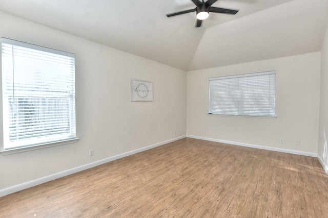 empty room with ceiling fan, a healthy amount of sunlight, light hardwood / wood-style flooring, and vaulted ceiling