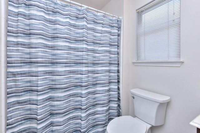 bathroom with toilet and a shower with shower curtain