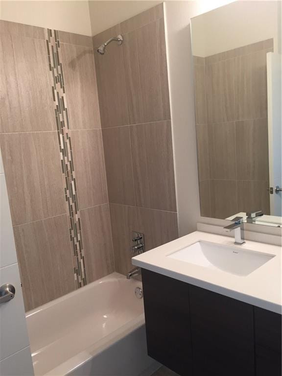 bathroom with tiled shower / bath and vanity