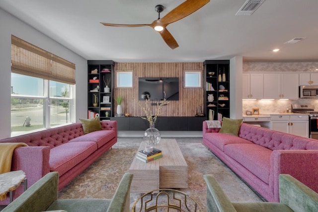 living room with built in features and ceiling fan