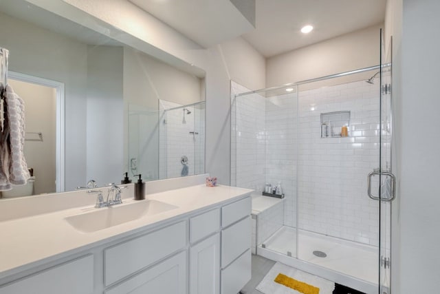 bathroom featuring a shower with door and vanity