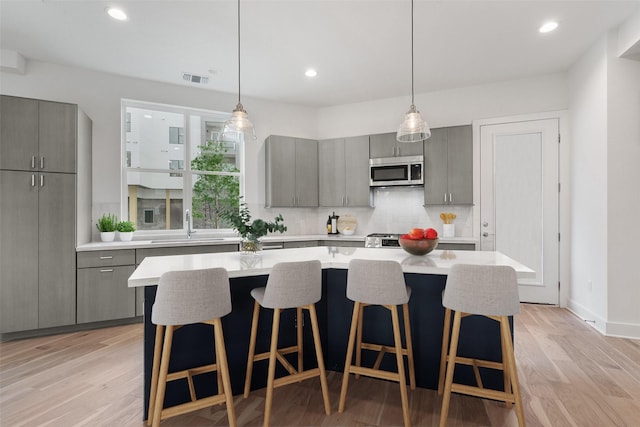 kitchen featuring a large island, backsplash, gray cabinetry, and light hardwood / wood-style flooring