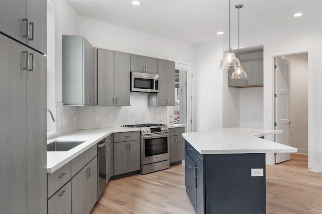 kitchen featuring hanging light fixtures, a center island, stainless steel appliances, gray cabinets, and sink