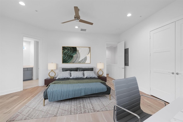 bedroom with connected bathroom, ceiling fan, and light hardwood / wood-style floors