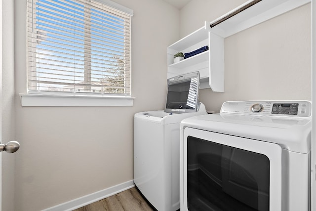 2213 Rocoso Trl, Leander, TX 78641 - laundry room featuring washer and clothes dryer, wood finished floors, healthy amount of natural light, and baseboards