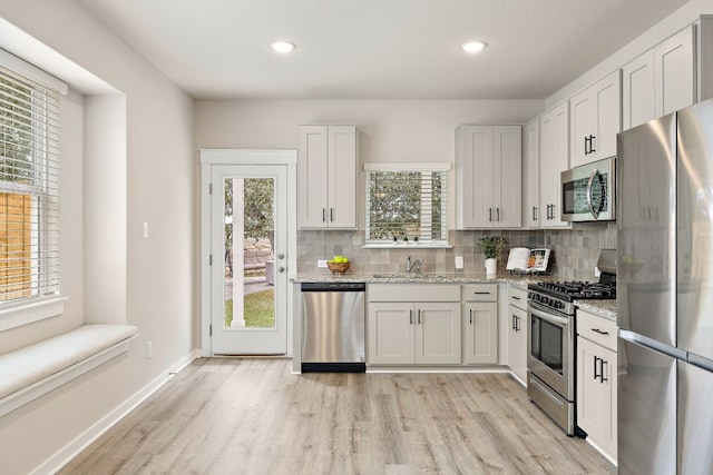 kitchen featuring white cabinets, appliances with stainless steel finishes, light stone counters, and decorative backsplash