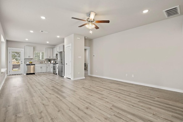 unfurnished living room with sink, ceiling fan, and light wood-type flooring