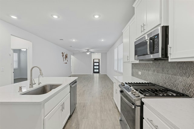 kitchen featuring sink, a center island with sink, white cabinetry, and appliances with stainless steel finishes