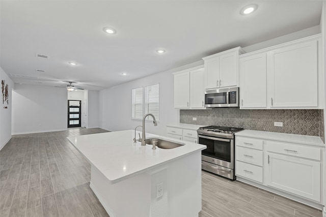 kitchen with sink, a kitchen island with sink, white cabinetry, and appliances with stainless steel finishes