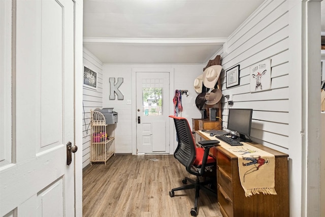 office area with light hardwood / wood-style flooring and wooden walls