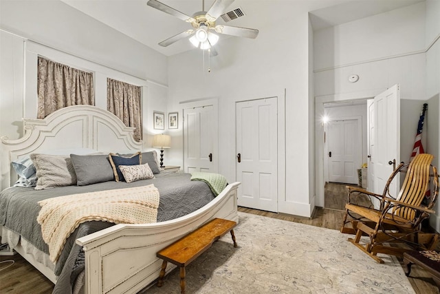 bedroom featuring ceiling fan, dark wood-type flooring, and a high ceiling