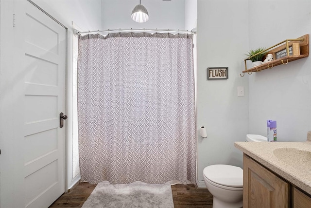 bathroom with toilet, a shower with shower curtain, hardwood / wood-style floors, and vanity