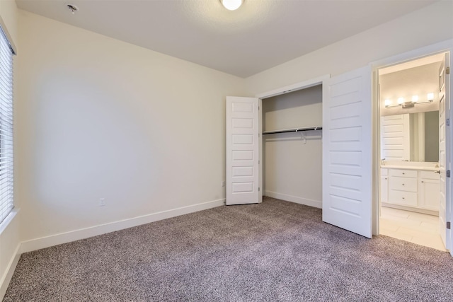 unfurnished bedroom with a closet, carpet, and connected bathroom