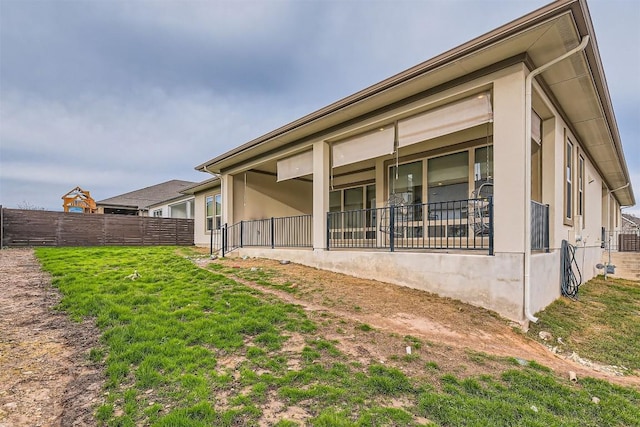 exterior space featuring stucco siding, fence, and a yard