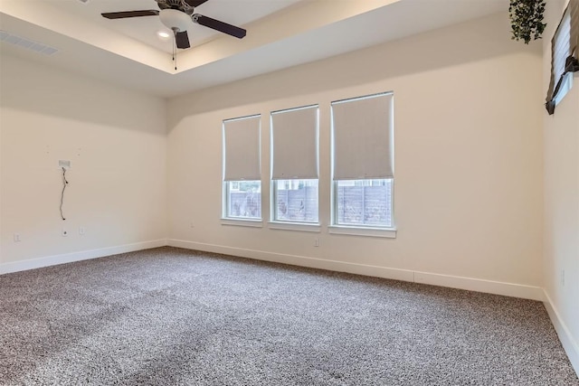 unfurnished room featuring baseboards, visible vents, a raised ceiling, a ceiling fan, and carpet floors