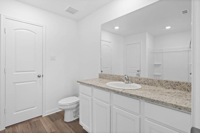 bathroom with a shower, toilet, vanity, and wood-type flooring