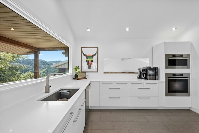 kitchen with sink, white cabinetry, vaulted ceiling with beams, and appliances with stainless steel finishes