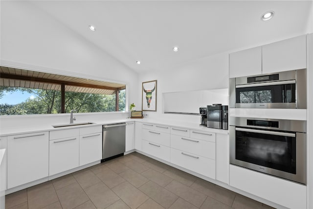 kitchen featuring appliances with stainless steel finishes, white cabinets, vaulted ceiling, and sink