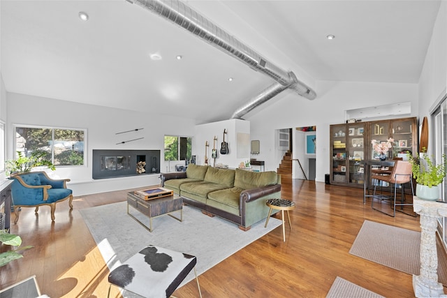 living room featuring high vaulted ceiling and light wood-type flooring