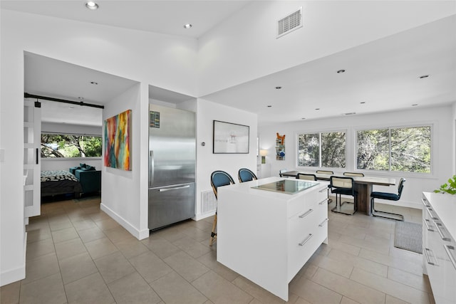 kitchen with stainless steel built in fridge, white cabinetry, a wealth of natural light, and a kitchen island