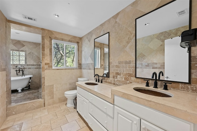 bathroom featuring toilet, tile walls, tile patterned floors, a bath, and vanity