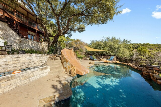 view of swimming pool with a water slide and a patio