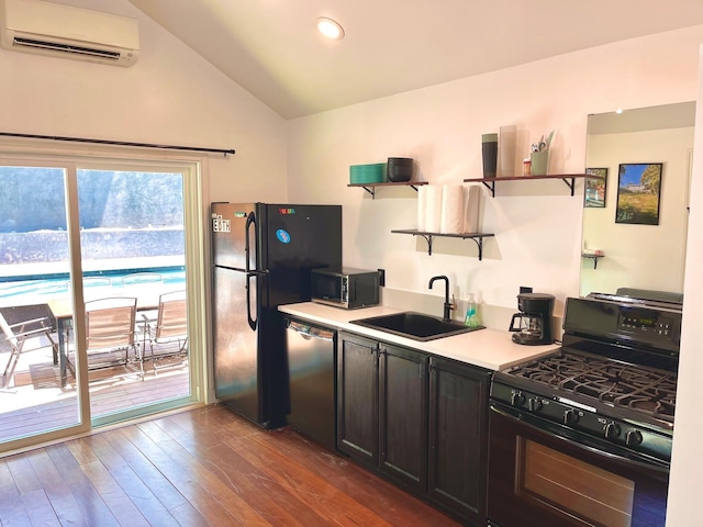 kitchen with a wall unit AC, vaulted ceiling, black appliances, dark hardwood / wood-style flooring, and sink