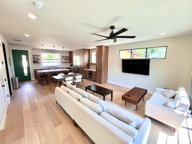 living room featuring ceiling fan, light wood-type flooring, and sink