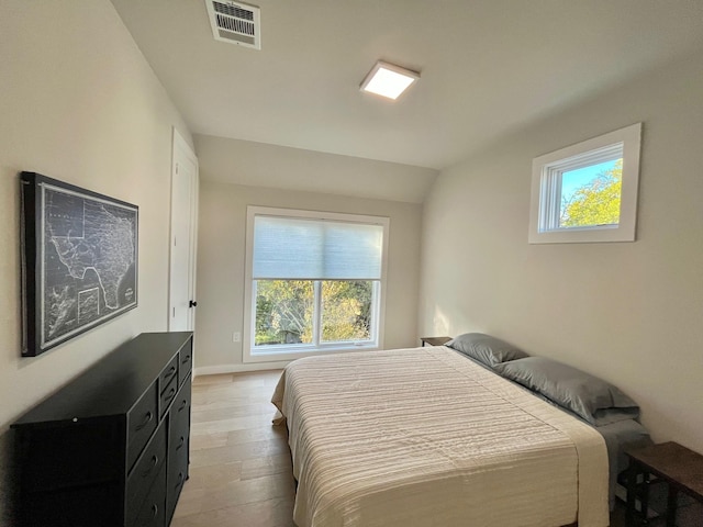 bedroom featuring light hardwood / wood-style flooring, multiple windows, and lofted ceiling