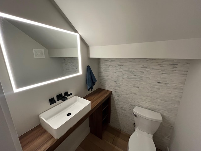 bathroom featuring sink, hardwood / wood-style floors, lofted ceiling, and toilet