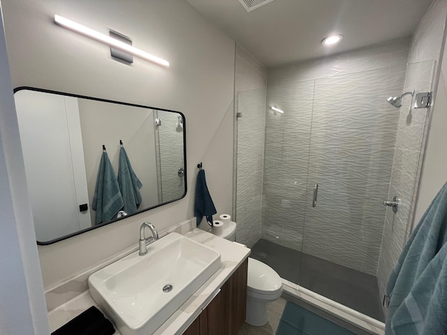 bathroom featuring a shower with door, vanity, and toilet