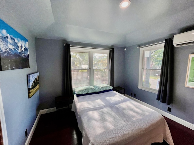 bedroom with dark wood-type flooring, a raised ceiling, a wall mounted air conditioner, and multiple windows