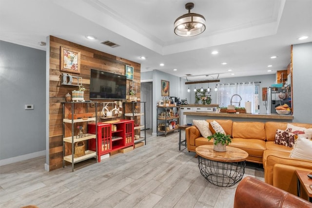 living room featuring a tray ceiling and light wood-type flooring