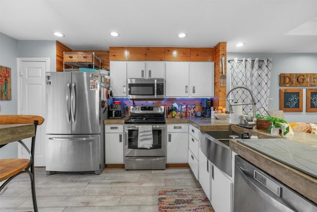 kitchen featuring stainless steel appliances, white cabinetry, sink, and backsplash