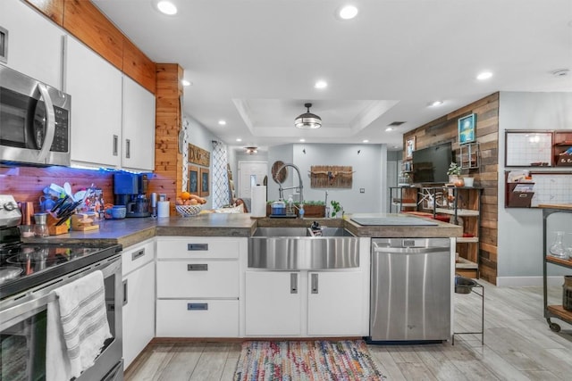 kitchen featuring appliances with stainless steel finishes, sink, white cabinets, decorative backsplash, and kitchen peninsula