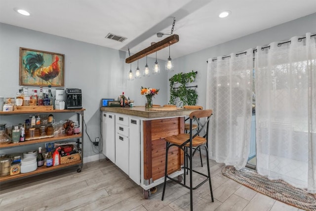 kitchen featuring white cabinetry, pendant lighting, kitchen peninsula, and a breakfast bar