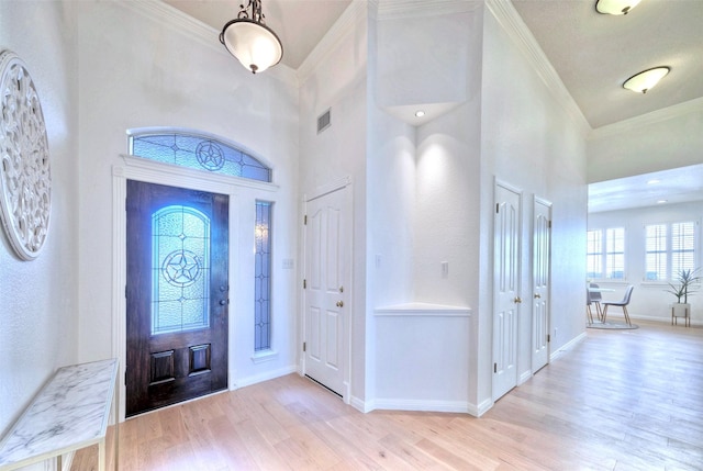 entrance foyer featuring a towering ceiling, crown molding, and light hardwood / wood-style flooring