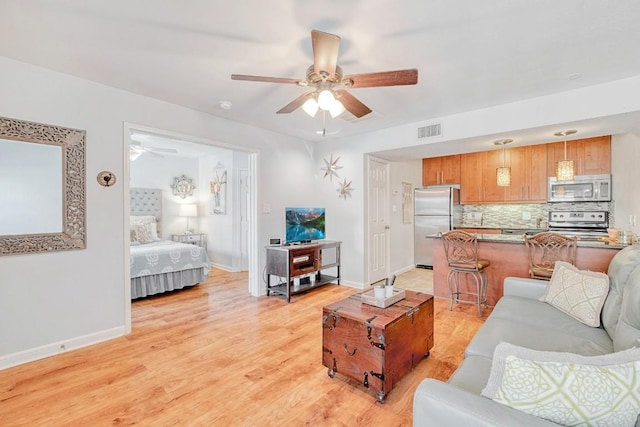 living area with light wood finished floors, baseboards, a ceiling fan, and visible vents