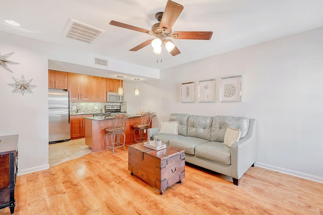 living room featuring sink, ceiling fan, and light hardwood / wood-style flooring