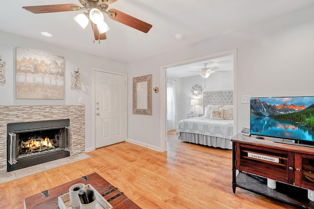 bedroom featuring a tile fireplace, ceiling fan, and hardwood / wood-style floors