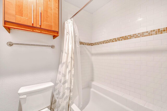 bathroom with shower / bath combination with curtain and toilet