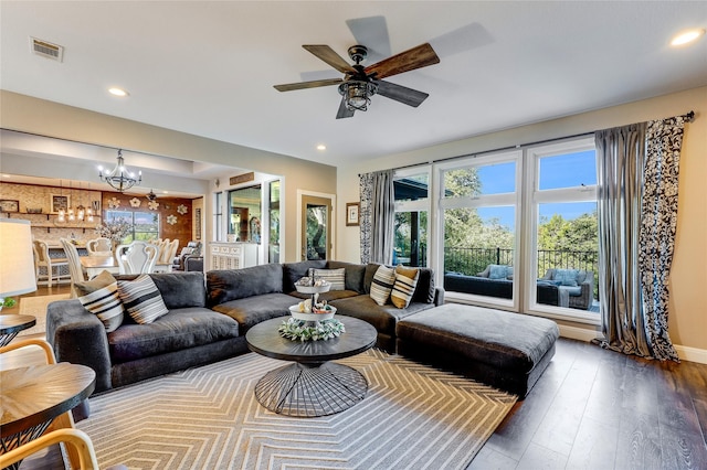 living room featuring ceiling fan with notable chandelier and dark hardwood / wood-style floors