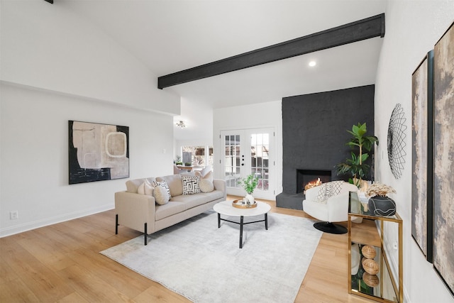 living room with light hardwood / wood-style floors, french doors, a large fireplace, and beamed ceiling