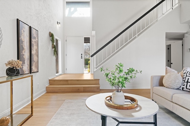 foyer entrance with a towering ceiling and light wood-type flooring