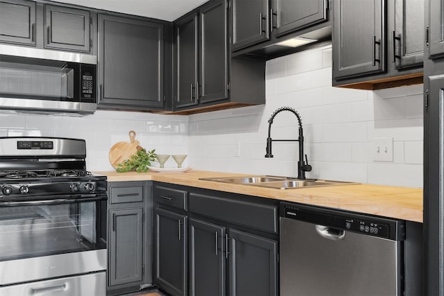 kitchen with appliances with stainless steel finishes, tasteful backsplash, sink, and butcher block counters