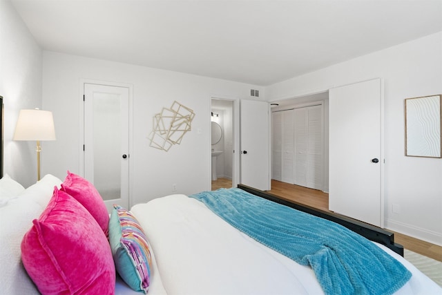 bedroom featuring ensuite bath and hardwood / wood-style floors